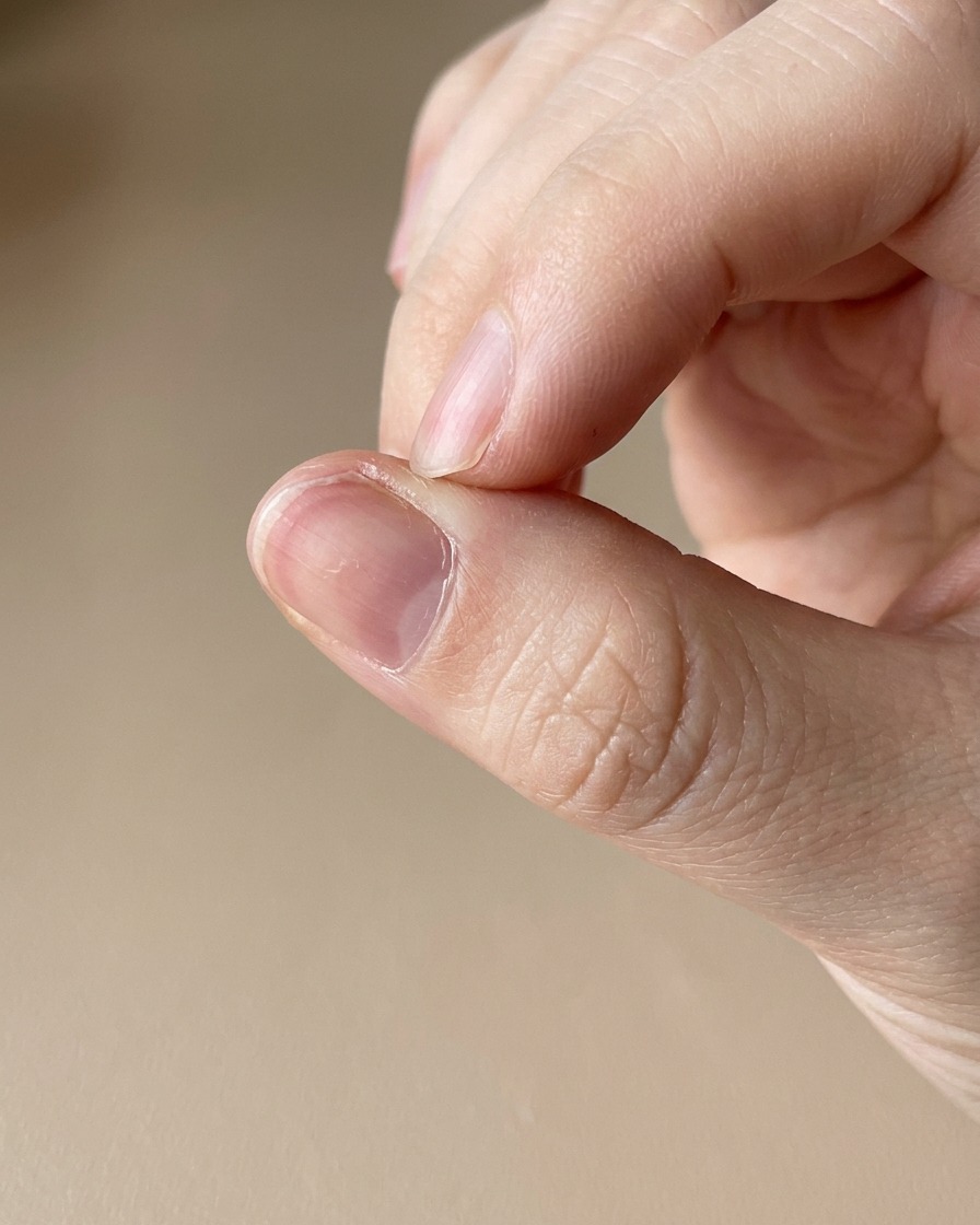 Dettaglio di un pennino per olio cuticole applicato sulla pelle intorno a ununghia appena curata.