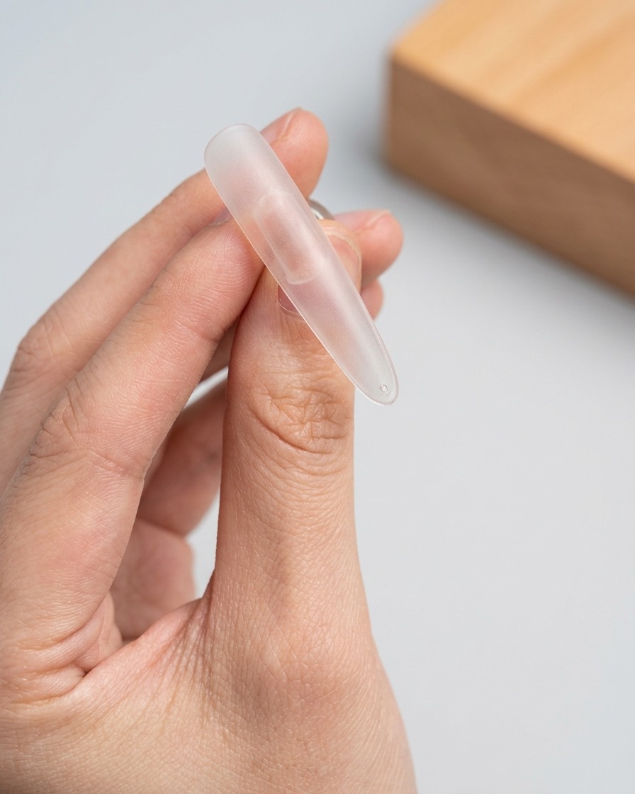 Un pennello applica uno strato di gel cat-eye scintillante sulla parte superiore di una tip trasparente.