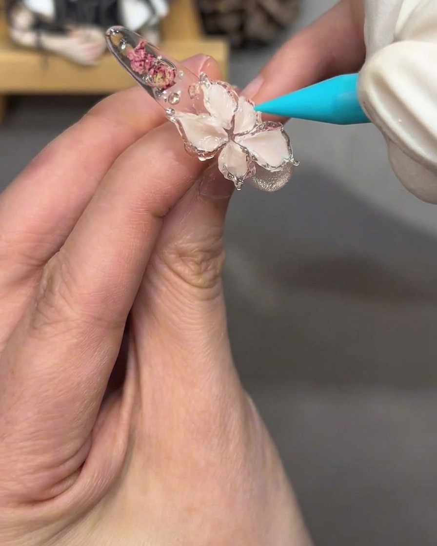 Vista ravvicinata del design floreale sullunghia, ora lucido e traslucido dopo lapplicazione del gel jelly trasparente.