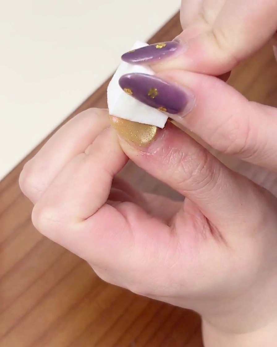 Una mano posizionata sotto una lampada UV/LED professionale per polimerizzare lo strato di gel sfumato.