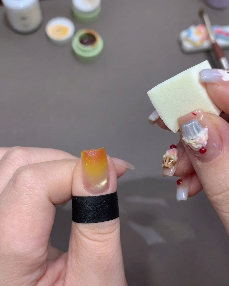 Una spugna per trucco che picchietta smalto gel arancione brillante sulla punta di ununghia per intensificare leffetto tramonto.