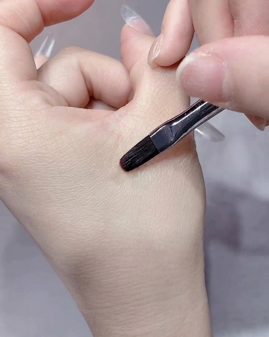 Un pennello liner sottile che definisce con cura i bordi del gel vicino alle cuticole.