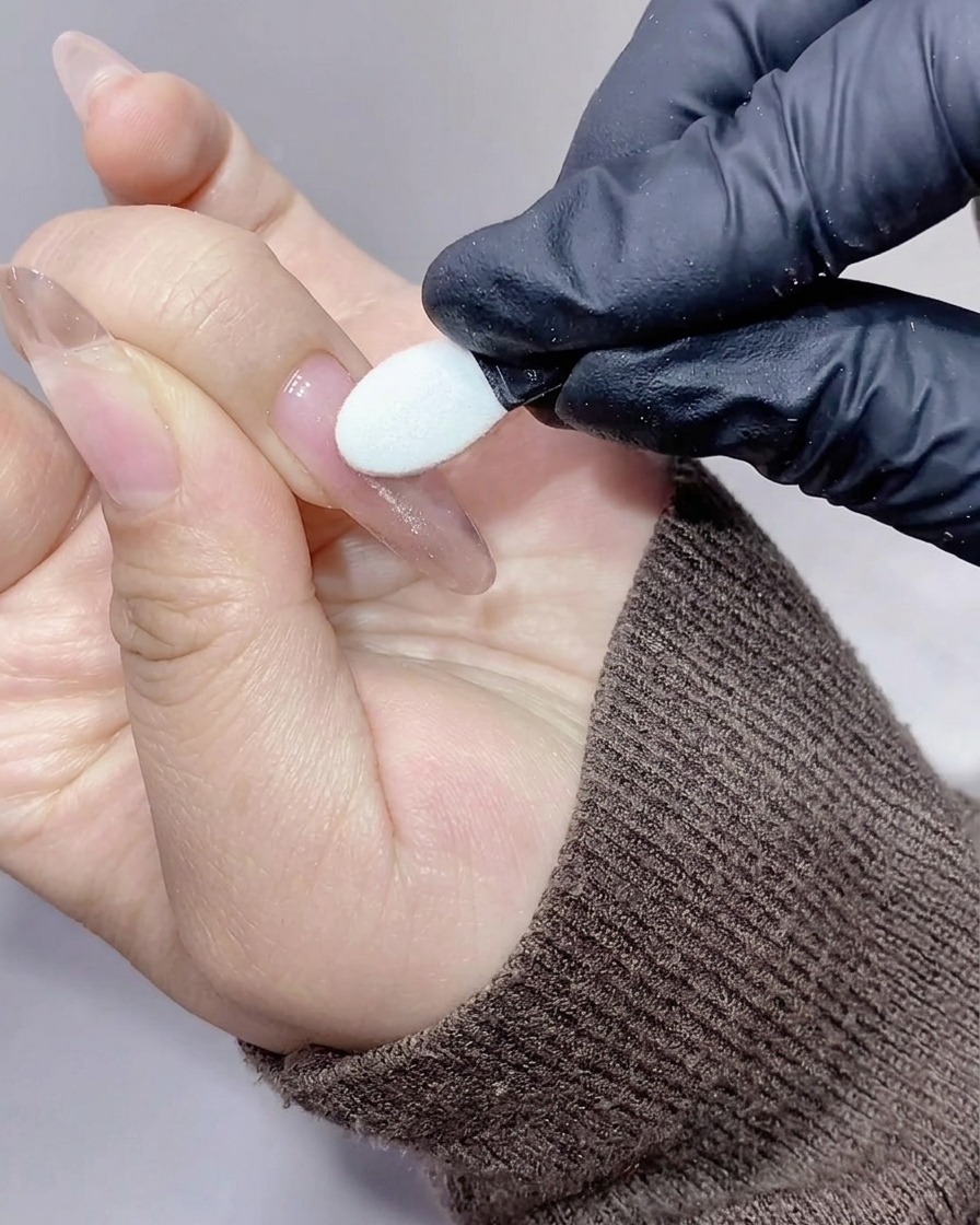 Un applicatore in silicone che strofina polvere aurora cangiante sulla superficie dellunghia.