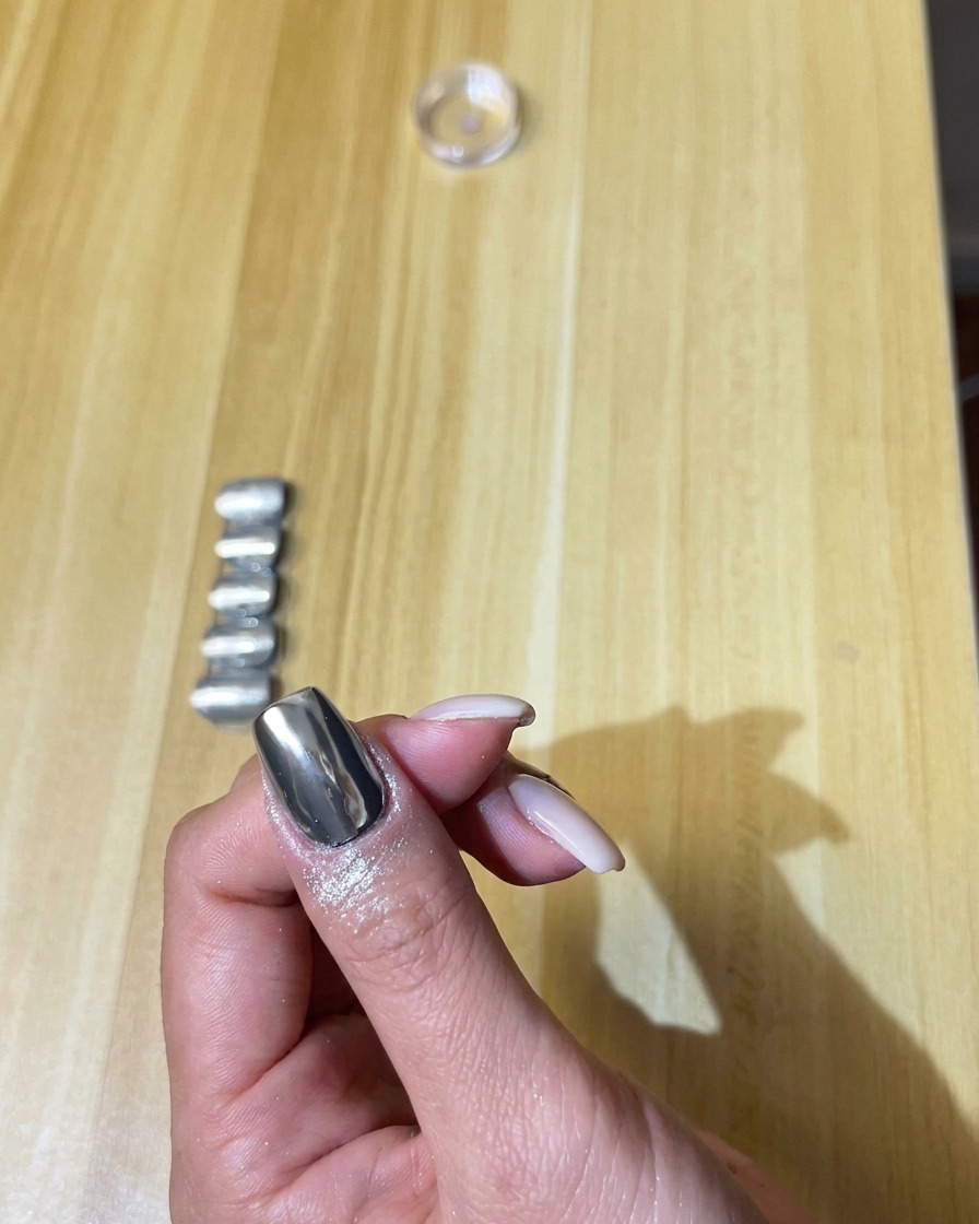 Un morbido pennello da trucco spolvera delicatamente la polvere cromo argento in eccesso dallunghia.