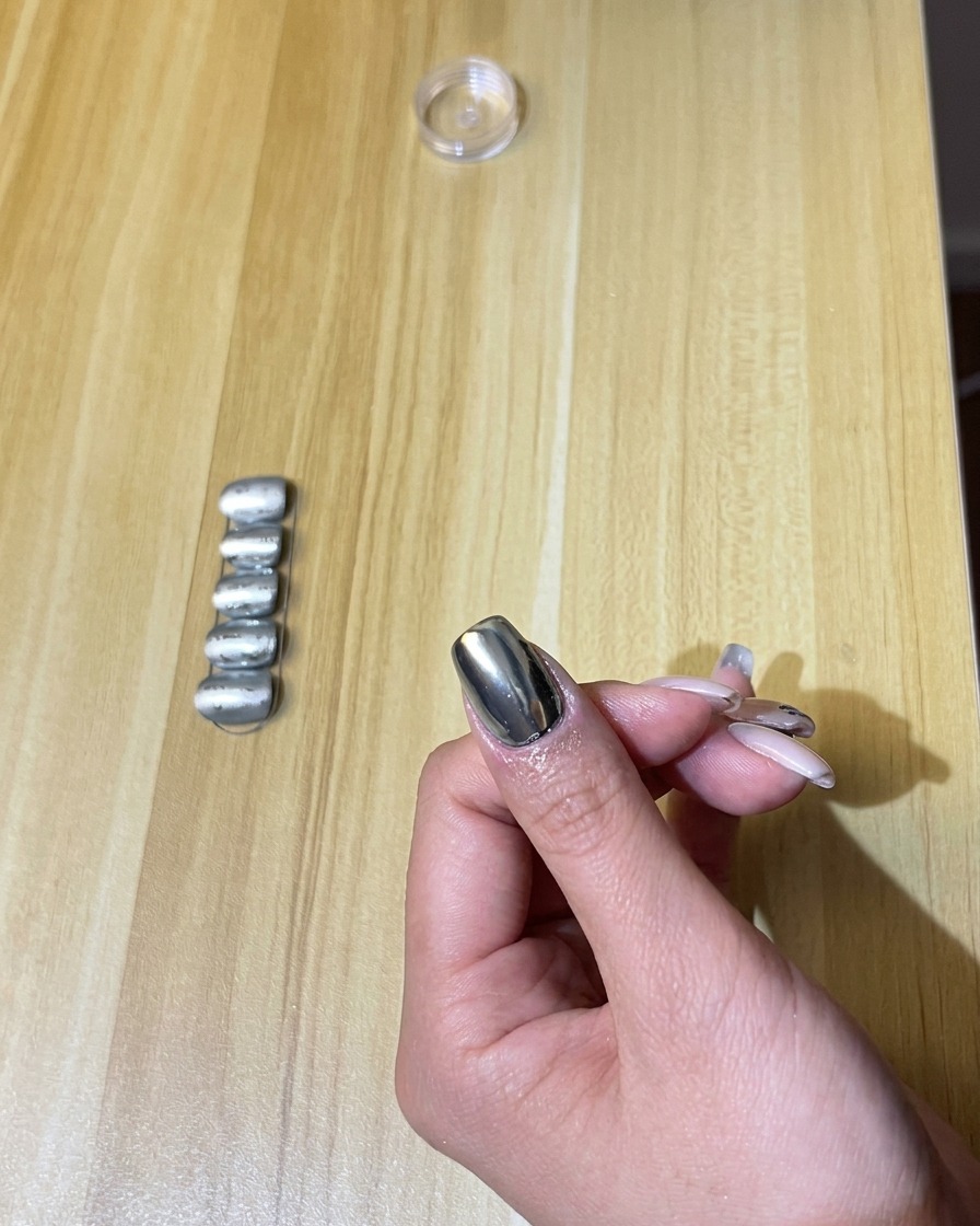 Una mano con unghie cromate allinterno di una lampada per unghie UV/LED accesa.