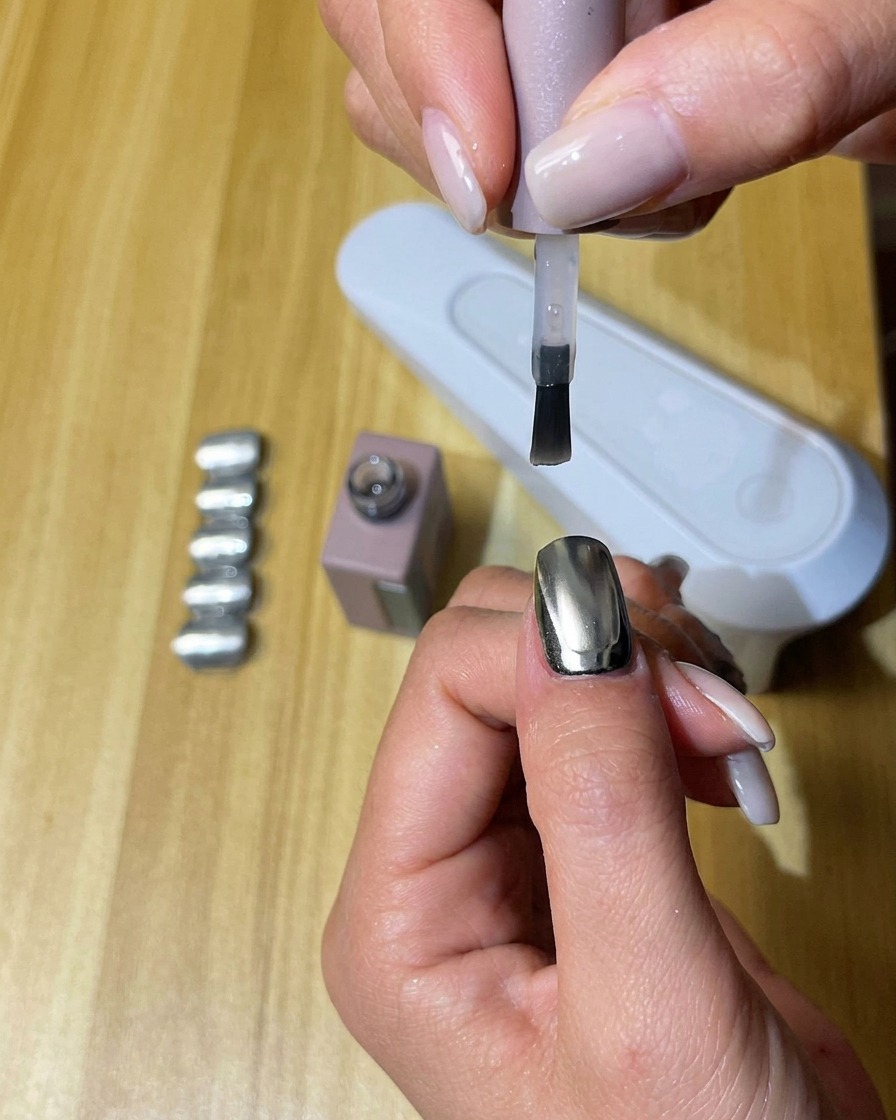 Una mano con unghie rivestite di top coat opaco durante la polimerizzazione allinterno di una lampada UV/LED.