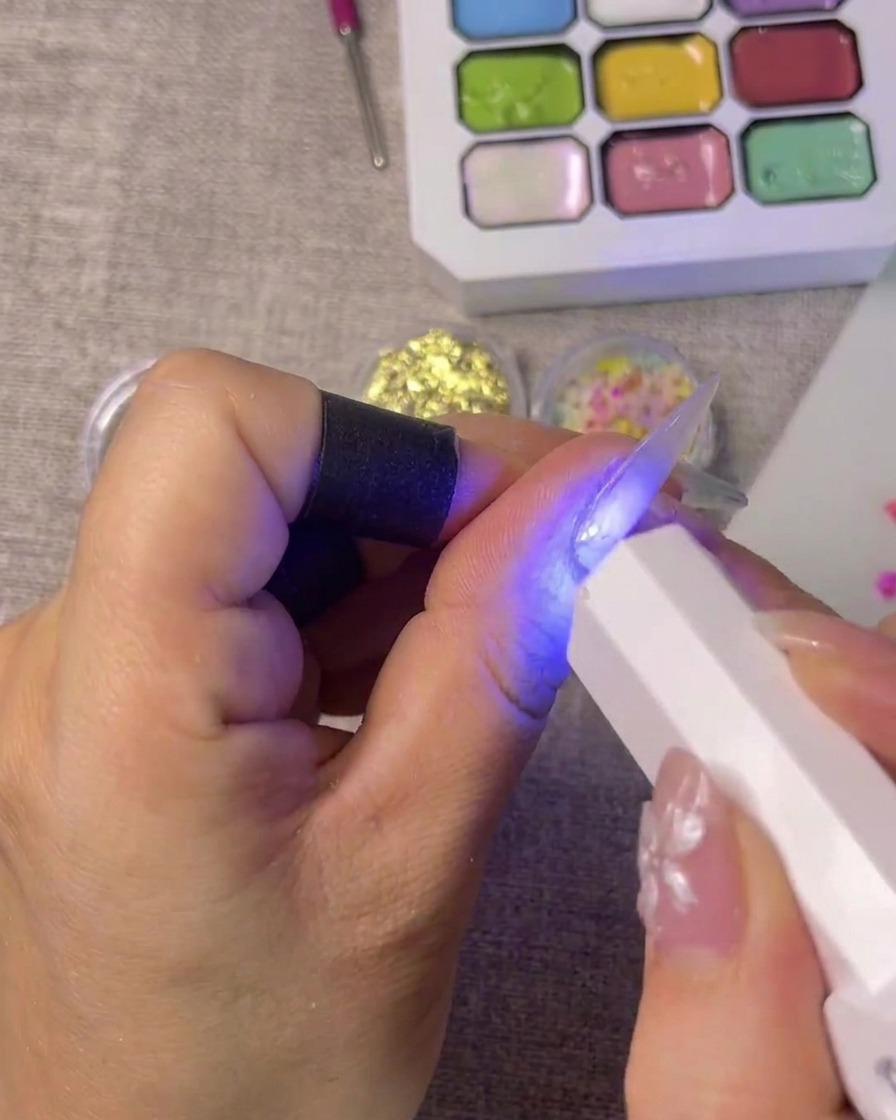 Un adesivo per french manicure posizionato con precisione sulla punta di ununghia.