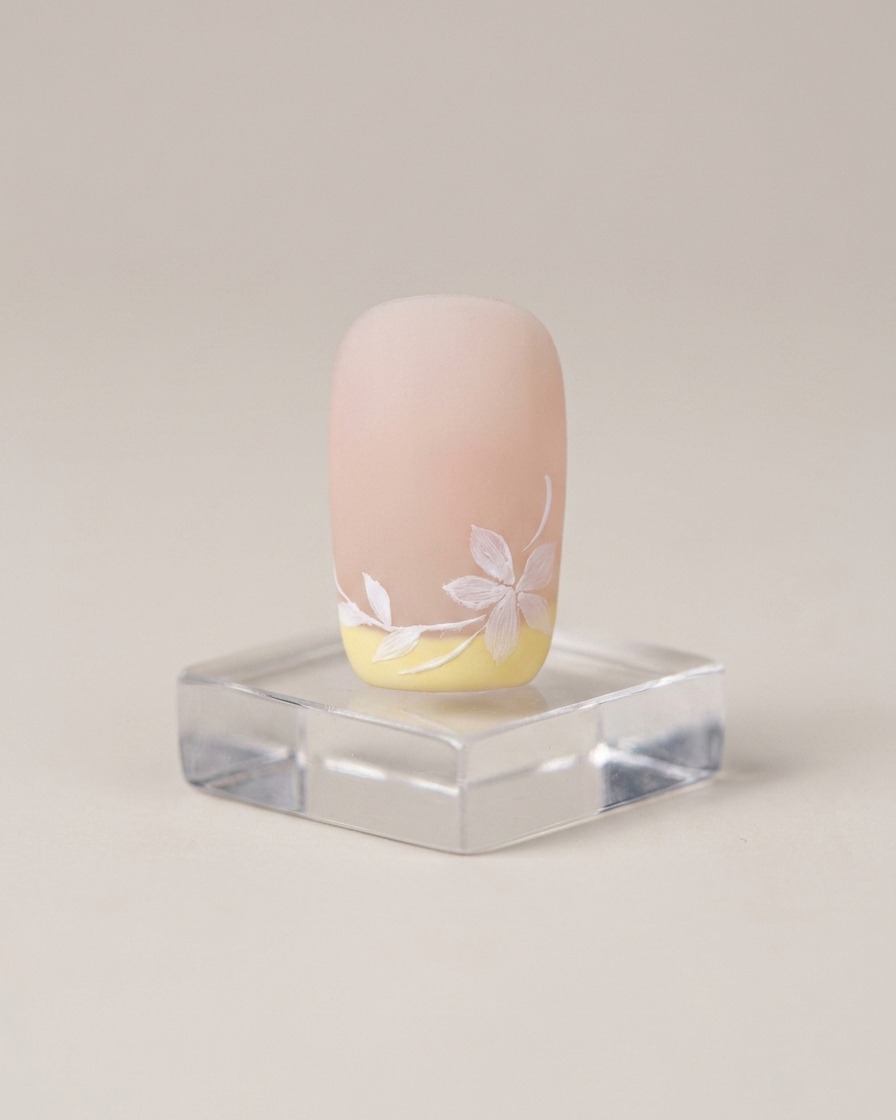 Un pennello applica uno strato sottile di base coat nude su ununghia naturale.