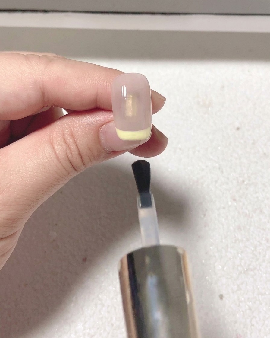 Un pennello applica un top coat opaco trasparente sopra lunghia con french rossa.