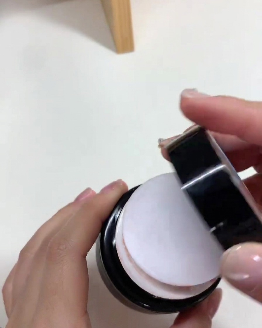 Un pennello applica uno strato uniforme di smalto gel nude su ununghia ricostruita.