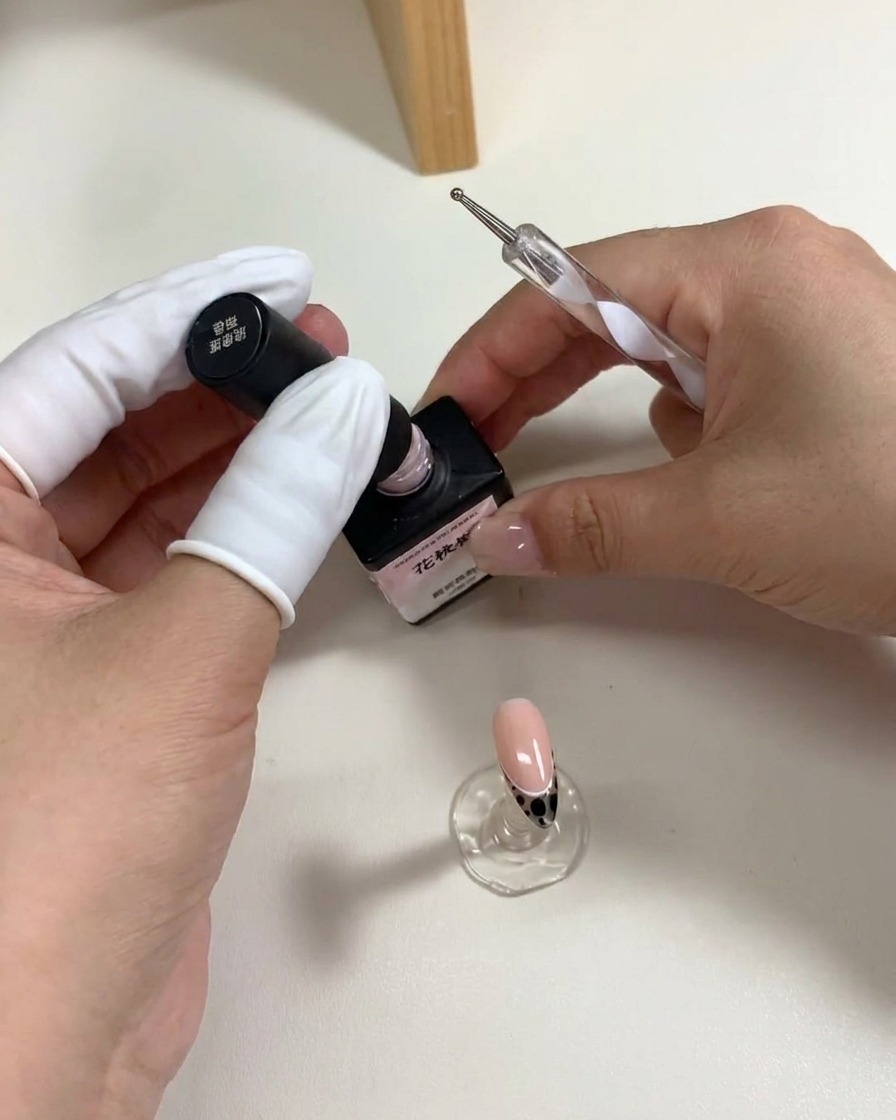 Un dotter posiziona cinque pois di gel rosa sulla superficie dellunghia per creare la forma di un fiore.