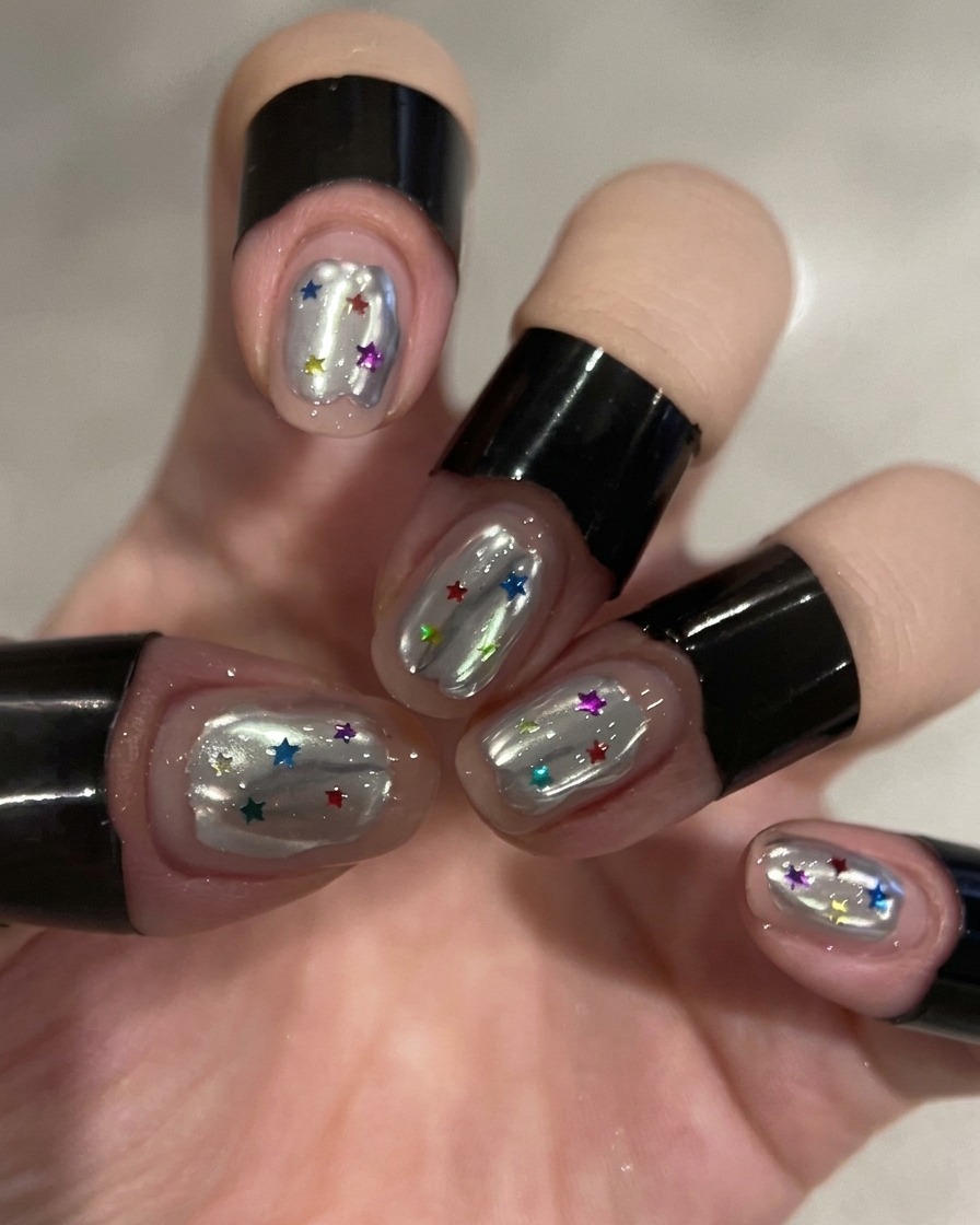 Pennello che applica un top coat trasparente su ununghia color argento cromo.