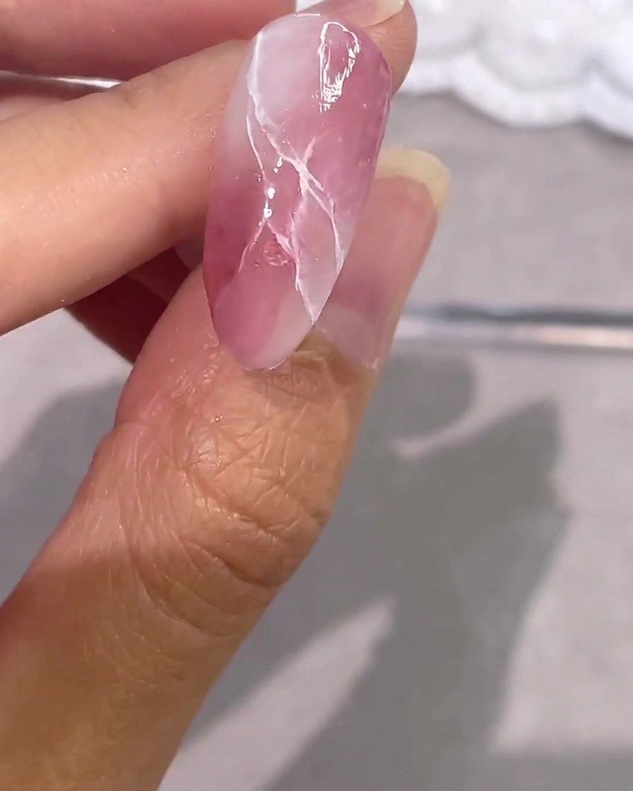 Ununghia in gel effetto marmo rosa completamente finita con accenti argento e un top coat ultra lucido.