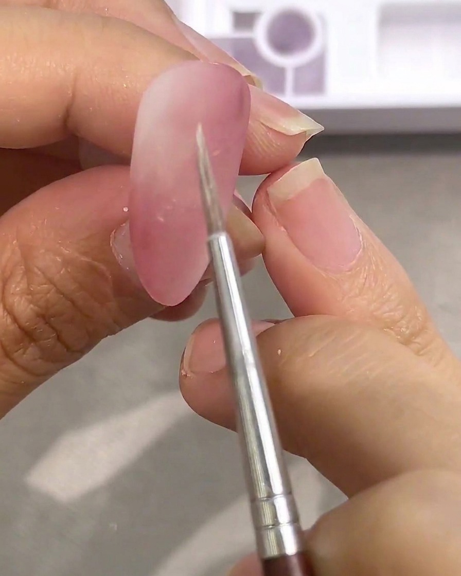 Primo piano di un pennellino di precisione che preleva del colore ad acquerello bianco da una tavolozza.