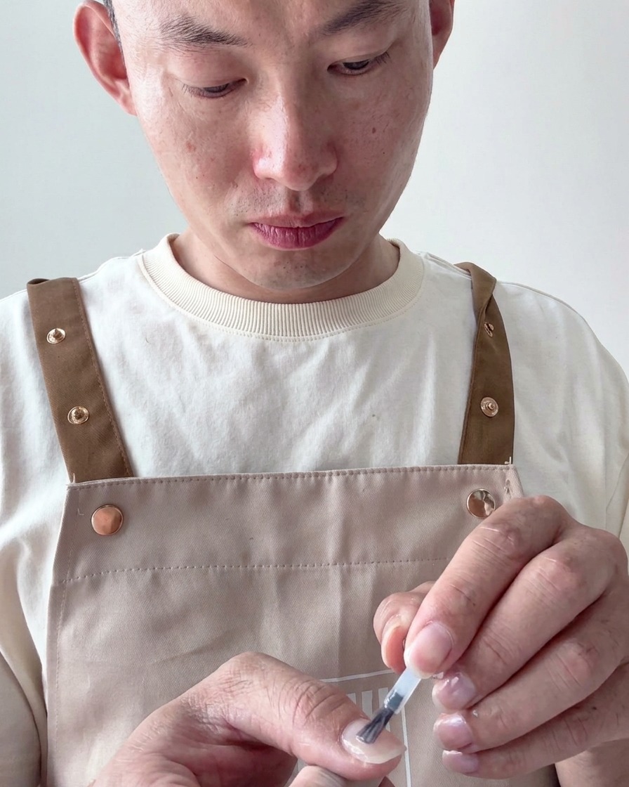 Un pennello per unghie applica uno smalto gel bianco latte velato su una tip preparata.