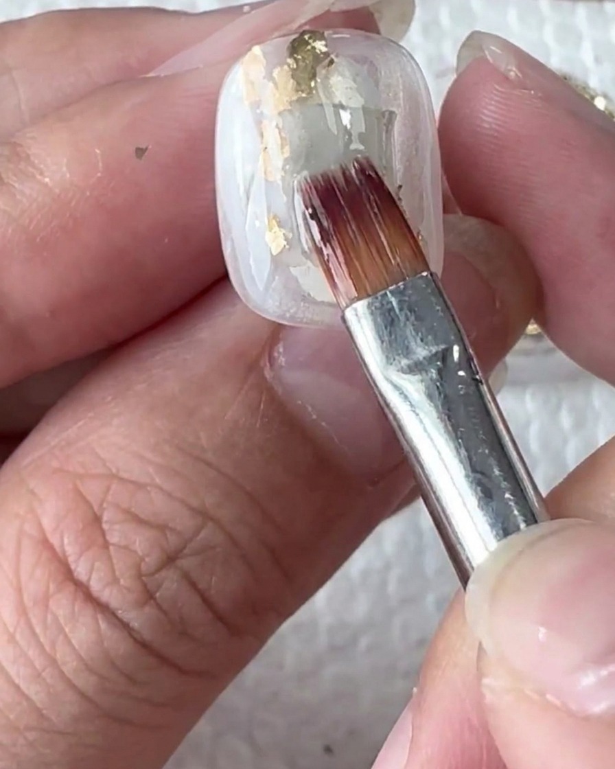 Gocce di gel bianco sulla superficie umida dellunghia.