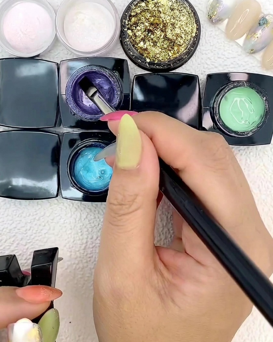 Un pennello piatto per nail art applica gel blu su una tip.