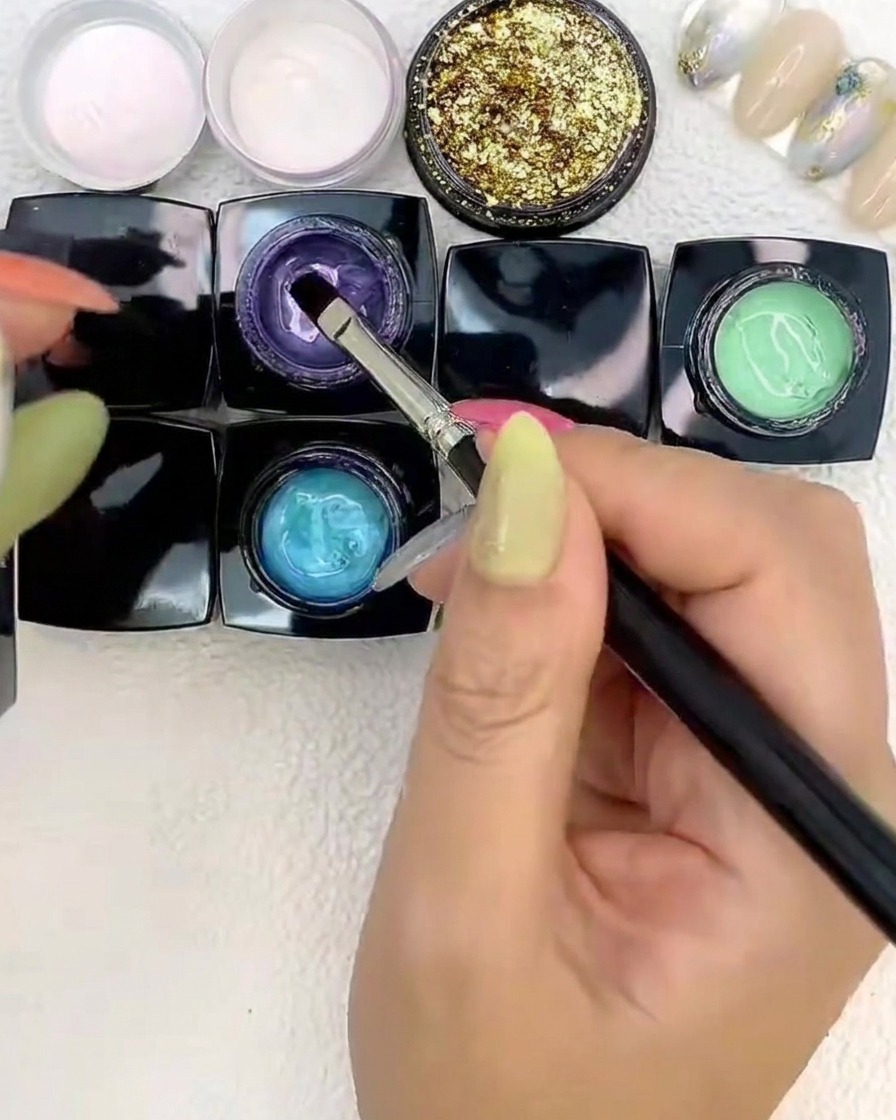 Un pennello posiziona gel viola accanto ai gel blu e verde.
