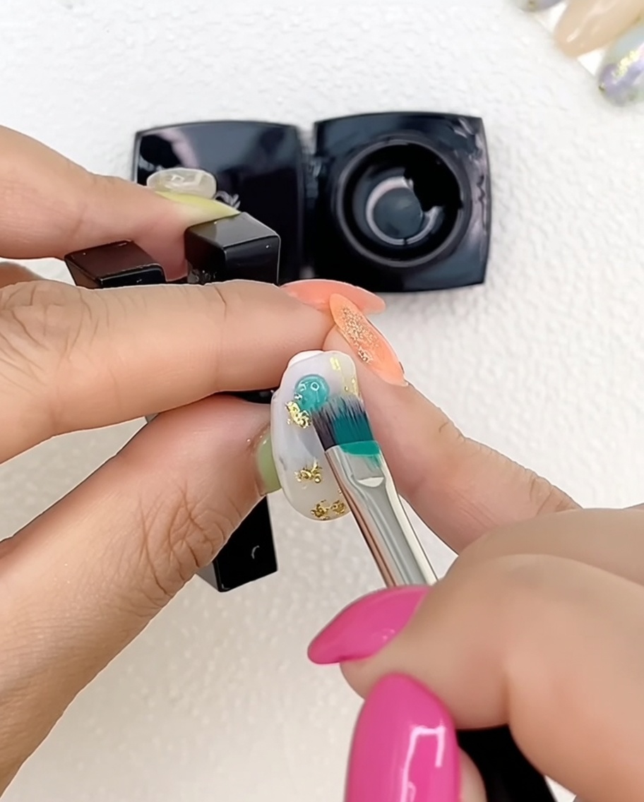 Primo piano di una mano con unghie decorate con gel multicolore sotto una lampada UV professionale.