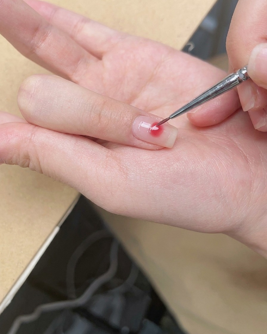 Un pennello di precisione sfuma i bordi del punto rosa per creare un delicato effetto ombre blush.