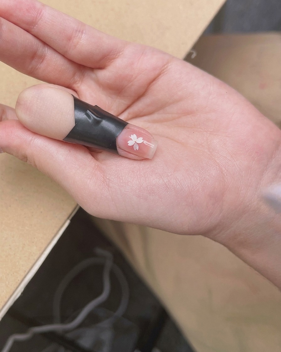 Una mano posizionata sotto una lampada UV/LED compatta, con il focus sulle unghie che ricevono la luce.