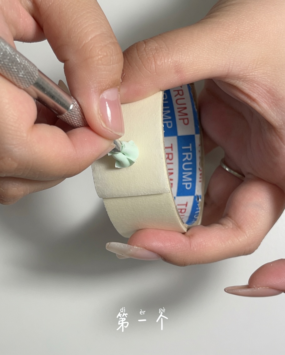 Uno spingicuticole in metallo usato per raschiare delicatamente la polvere dalla superficie di una spugnetta per trucco verde.