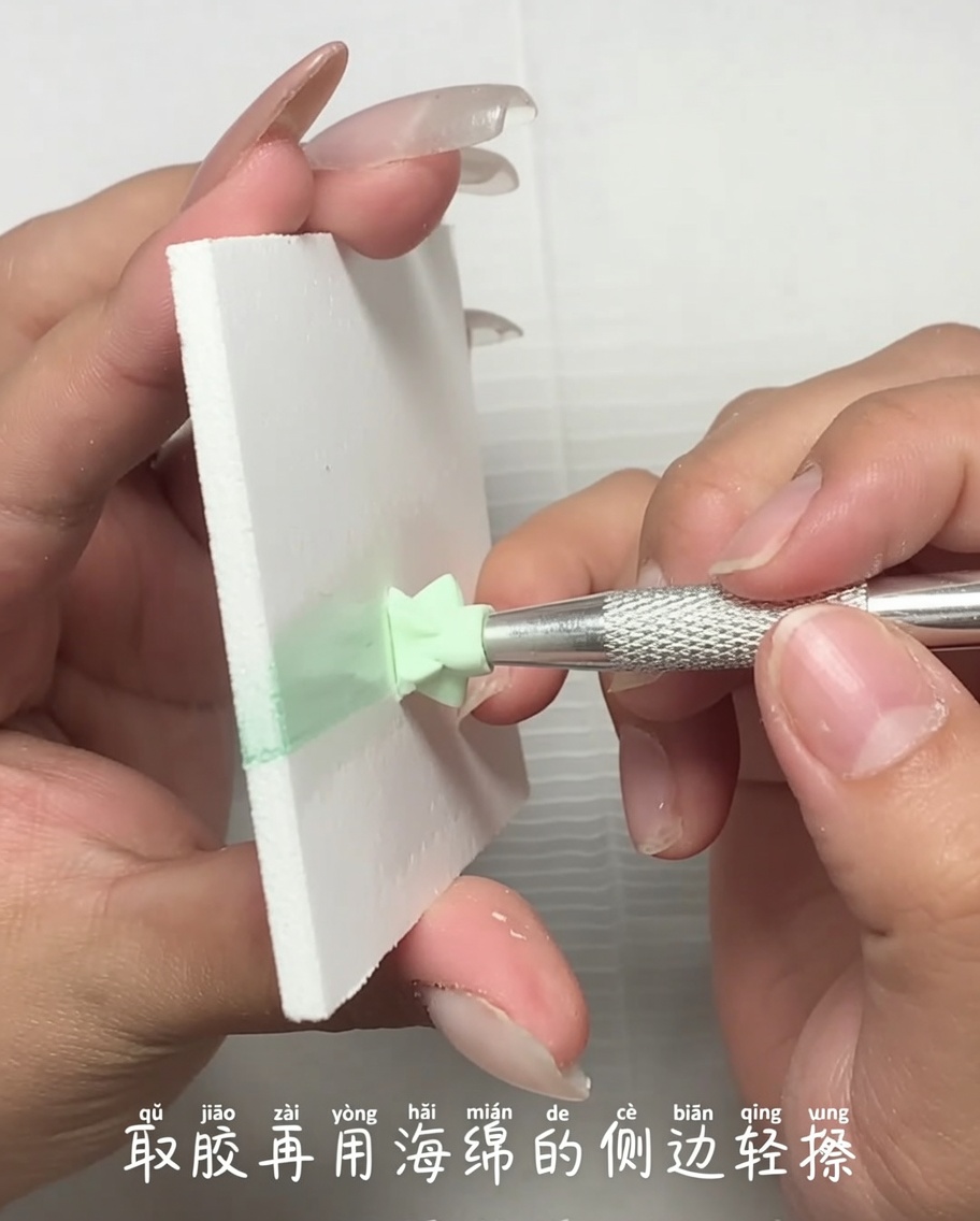 Vista ravvicinata di uno strumento in metallo che applica una piccola quantità di gel colorato dal bordo di una spugnetta per trucco.