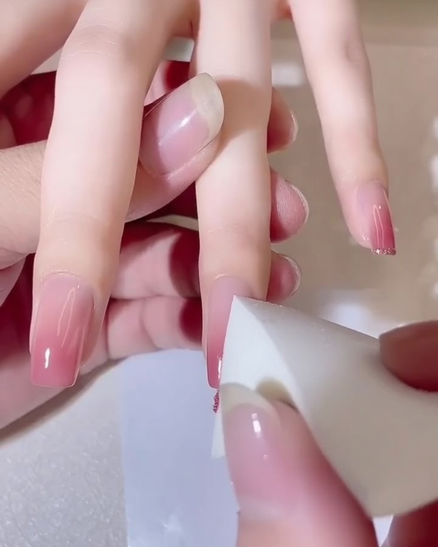 Primo piano di una spugnetta che tampona ununghia, mostrando lintensificarsi della sfumatura rosa.