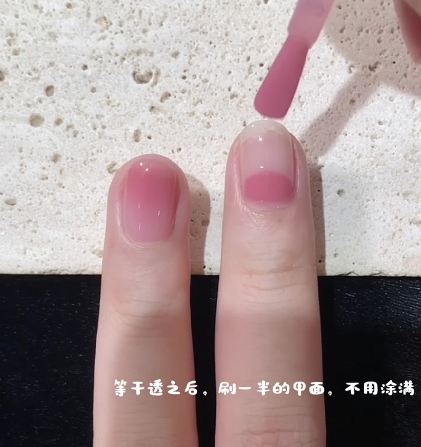 Un pennello per unghie che inizia lapplicazione dello smalto rosa a metà dellunghia per creare un effetto sfumato