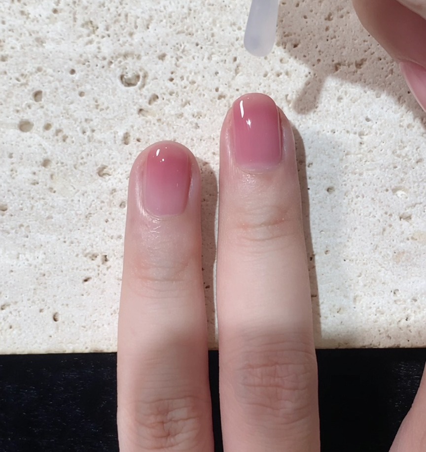 Un pennello che applica un top coat trasparente e lucido sopra il look gradient completato
