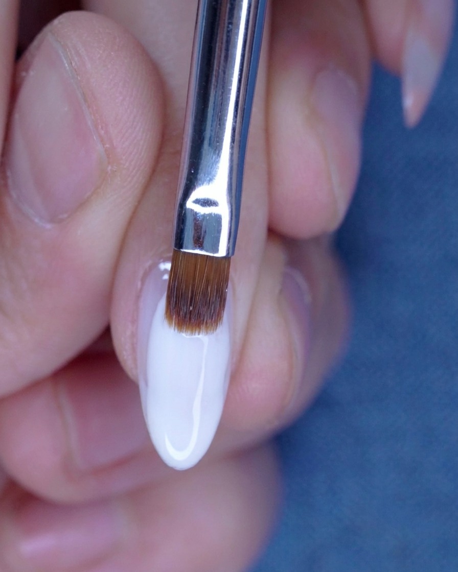 Sfumatura del secondo strato di gel nude con un pennello per una transizione perfetta.