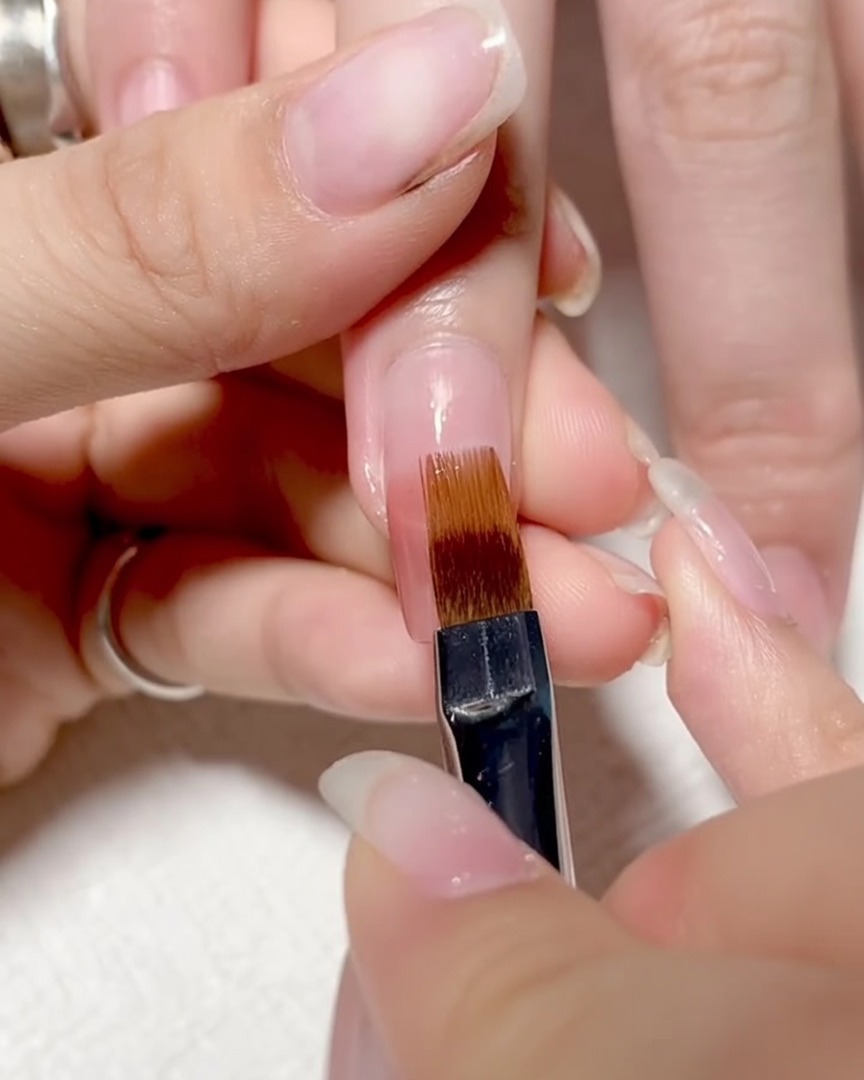 Pennello trascinato verso il basso sulla superficie dellunghia per sfumare i colori in un ombré liscio.