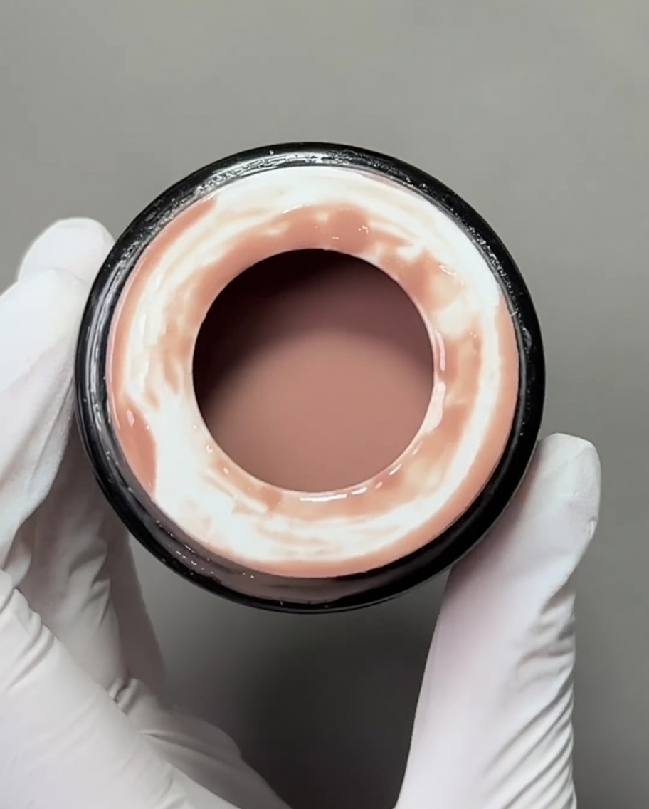 Vista ravvicinata di un pennello gel piatto che applica una base nude su una tip.