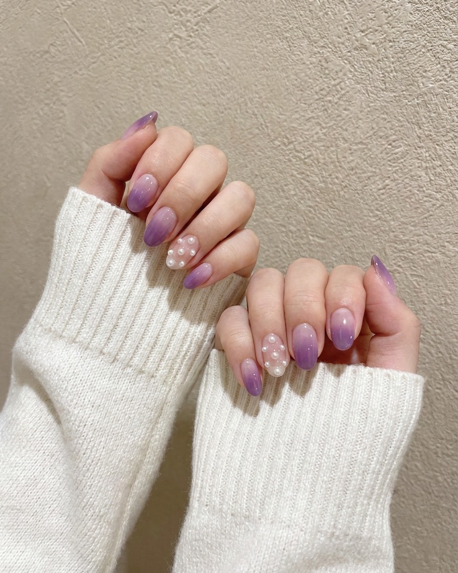 Un piccolo pennello di precisione che picchietta un gel viola scuro concentrato sulla punta di ununghia dipinta di viola chiaro.
