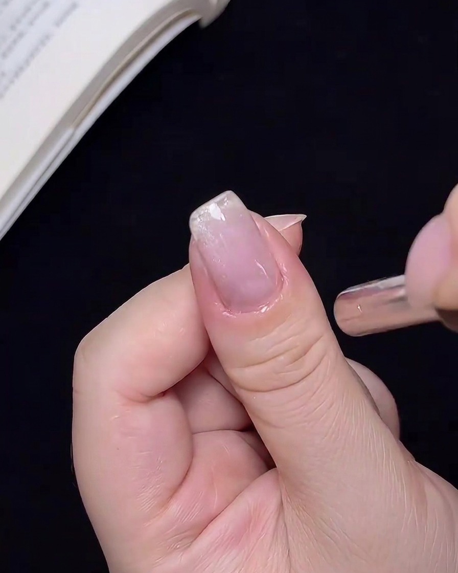 Vista ravvicinata di un magnete tenuto vicino a ununghia, che sposta la posizione delle particelle cat-eye.