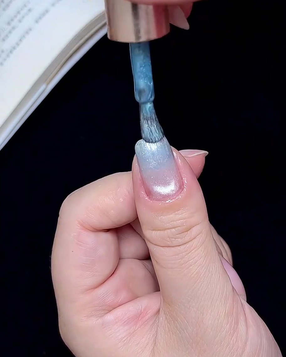 Un pennello che applica una piccola quantità di gel blu sulla punta dellunghia.