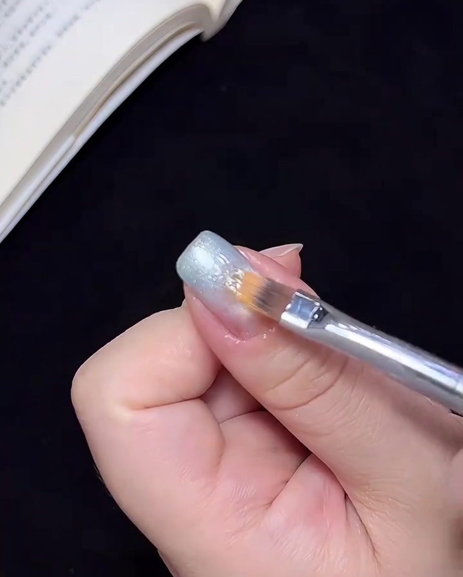 Un pennello che sfuma il gel blu verso il centro dellunghia per creare una transizione ombré.