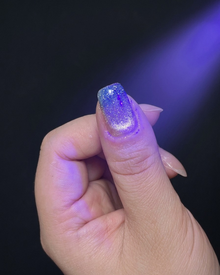 Una mano posizionata sotto la luce viola di una lampada UV/LED per la polimerizzazione.