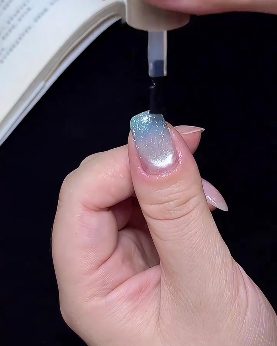 Una mano allinterno di una lampada UV/LED, con le unghie che vengono polimerizzate sotto la luce per il passaggio finale.
