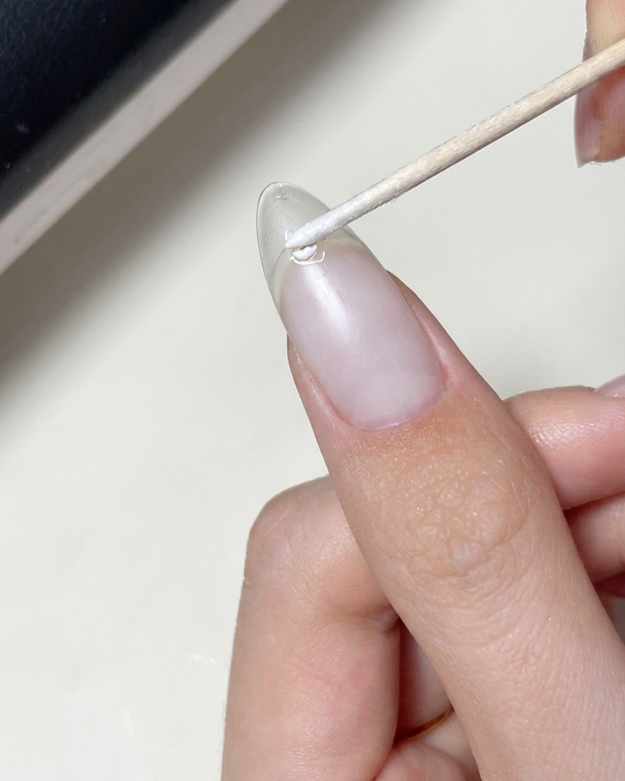 Un pennello che applica uno strato di gel trasparente sopra ununghia su cui è già stata applicata una decalcomania a stella.