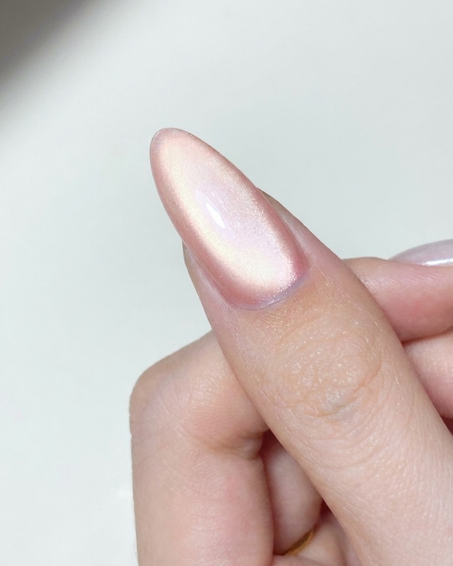 Un applicatore che stende polvere chrome aurora scintillante su una superficie di ununghia in gel polimerizzata.