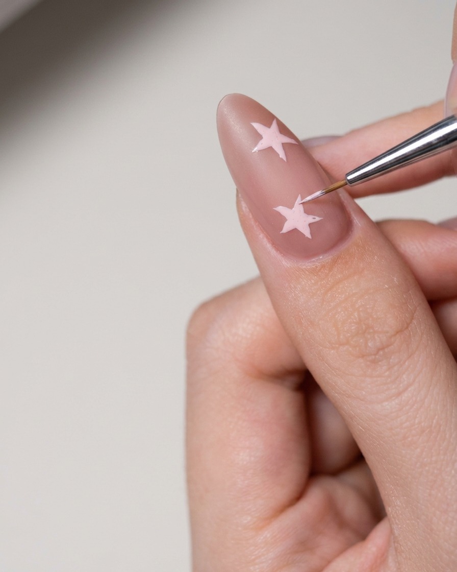Un piccolo strumento che applica pasta per nail art bianca per riempire una forma a stella sullunghia.