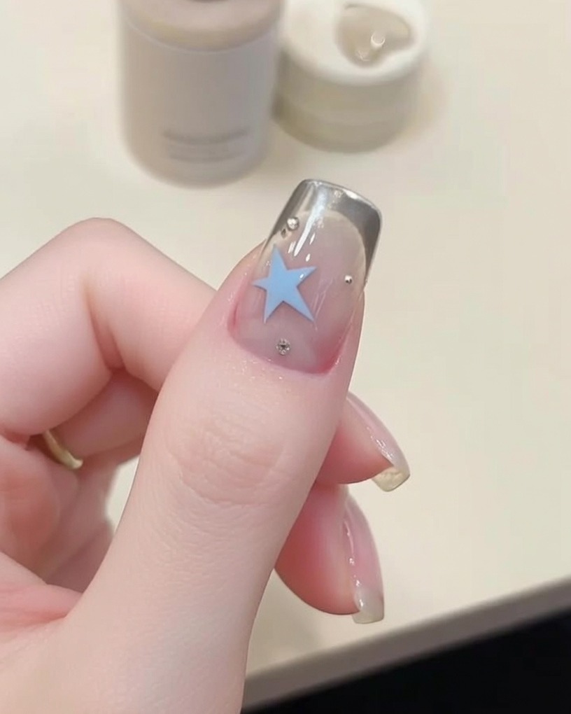 Un pennello a punta sottile che applica gel blu per creare una forma a stella.