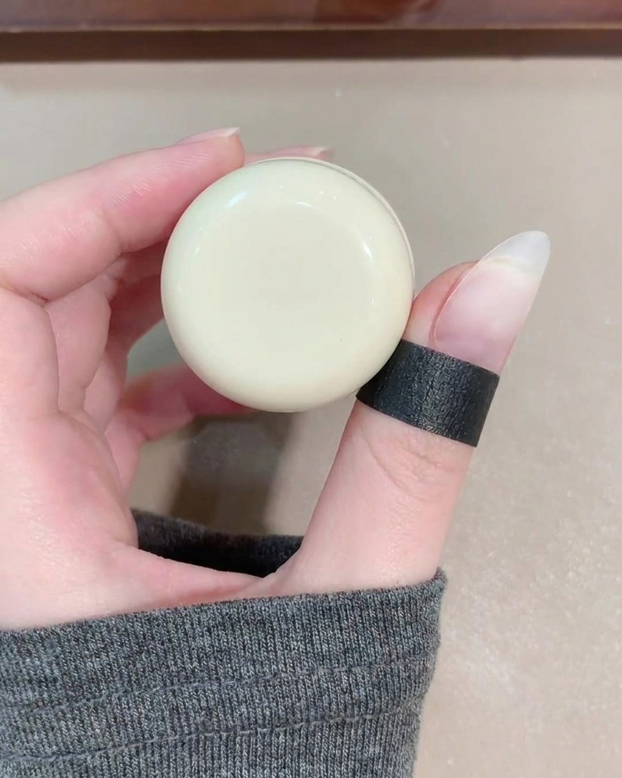 Un pennello per gel applica uno smalto cat eye blu trasparente su ununghia.