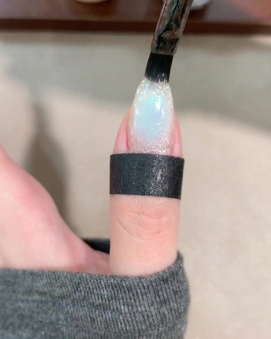 Un pennello applica uno strato trasparente di base coat sopra lunghia decorata.