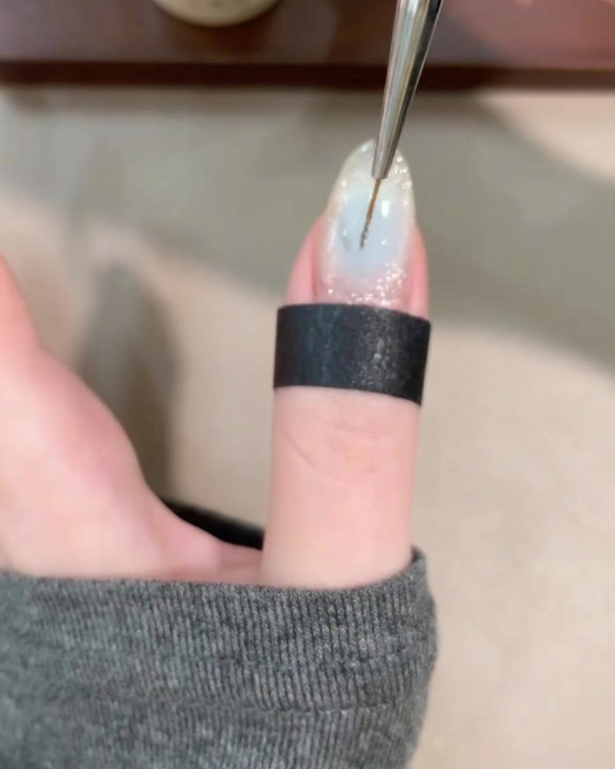 Un pennello sottile disegna linee sottili e vorticose su una base di gel trasparente.