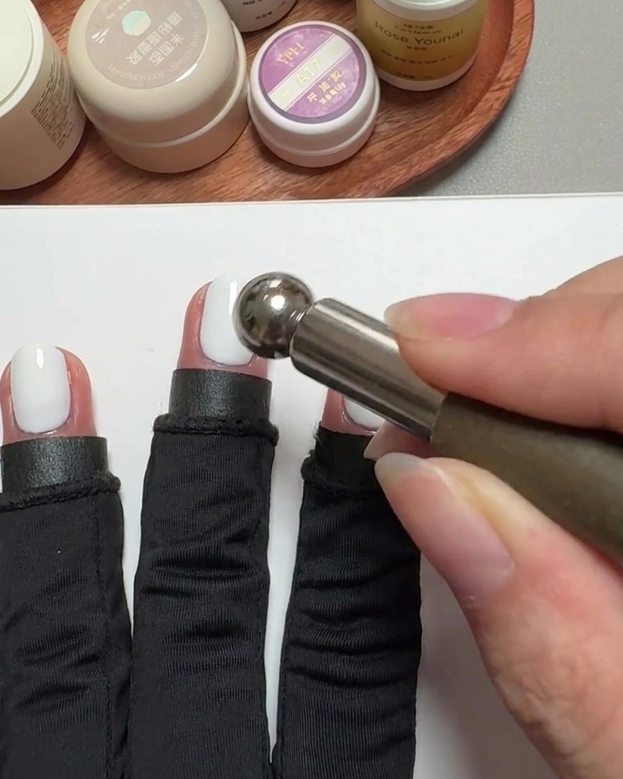 Primo piano di un magnete cilindrico che si libra sopra ununghia rivestita di gel per creare un effetto cat-eye.