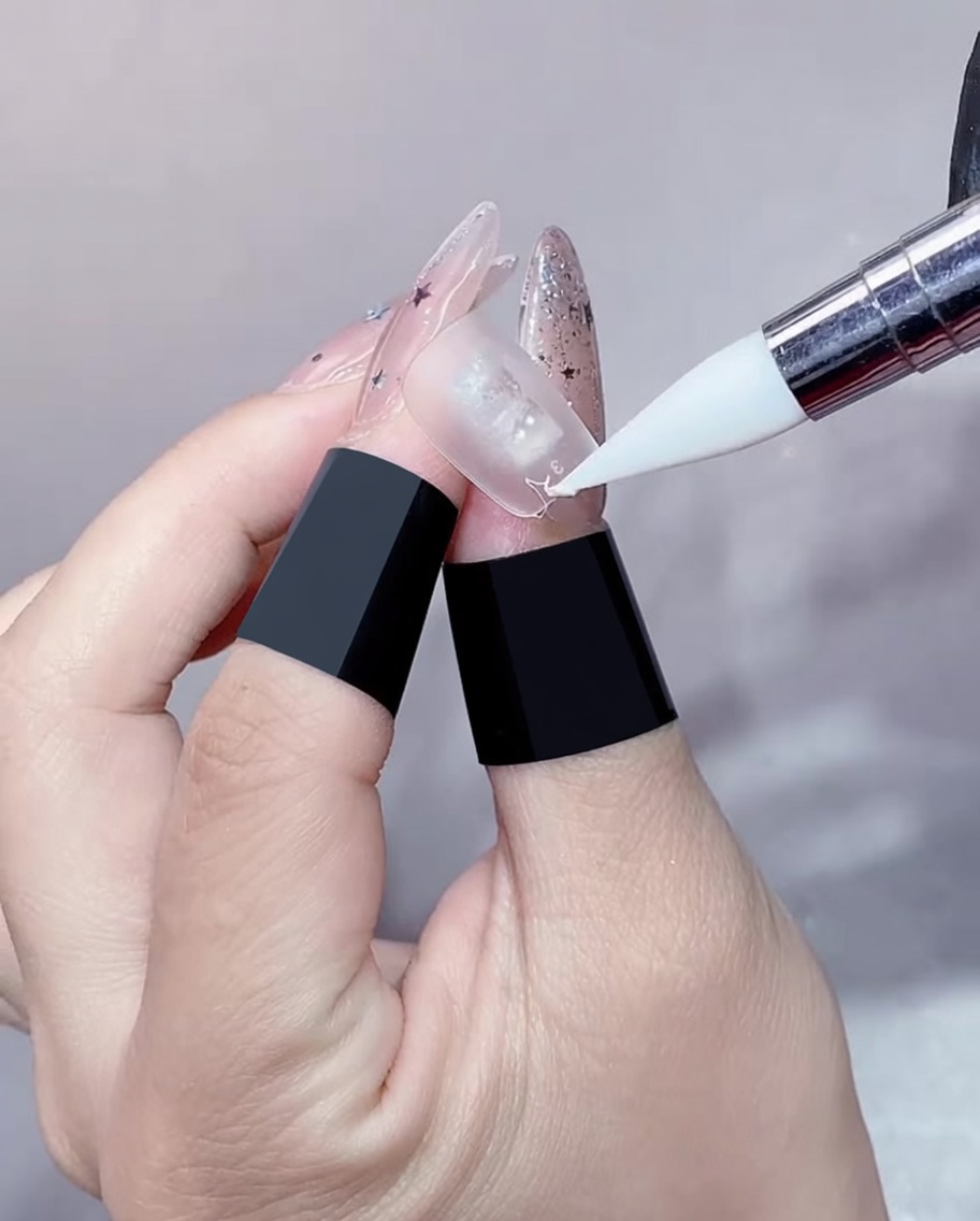 Un primo piano di un pennello per gel che applica un sottile strato di gel trasparente sul bordo di un allungamento dellunghia.