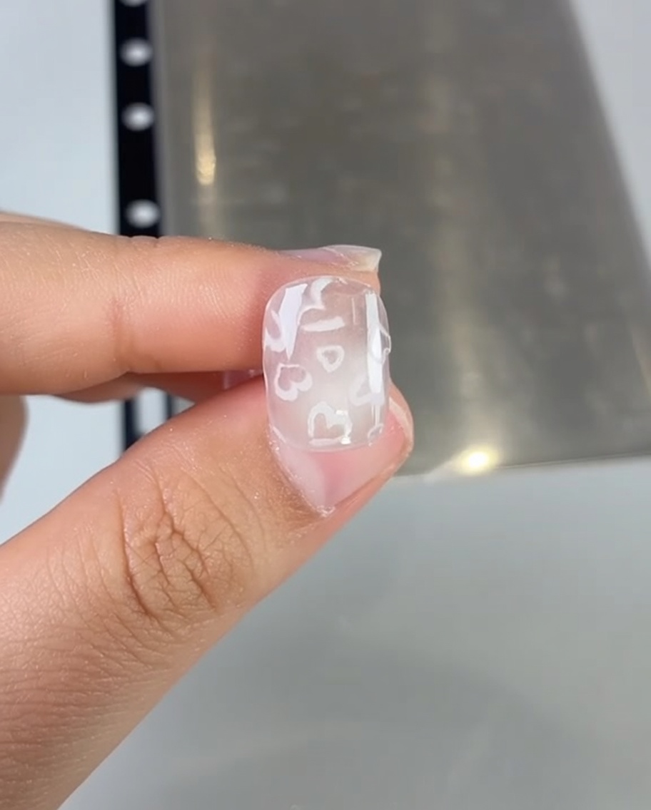 Dettaglio di un pennello che applica smalto gel rosa su ununghia.