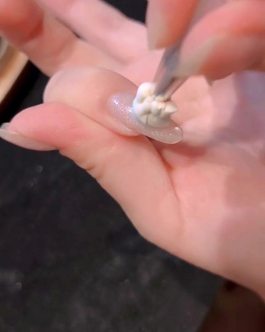 Una piccola goccia di gel blu che viene picchiettata al centro di ununghia con un pennello.